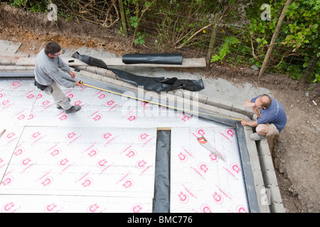 Builders lay under floor insulation into a house extension in Ambleside, UK. Stock Photo