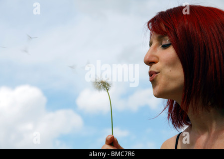 A woman blowing a dandelion. Stock Photo