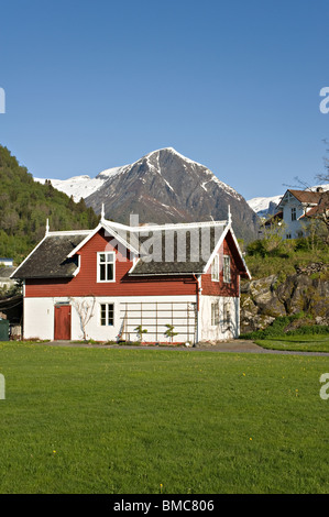 Small Norwegian House in Grounds of Kviknes Hotel Balestrand with Snow Covered Mountain Peaks Sognefjord Norway Stock Photo