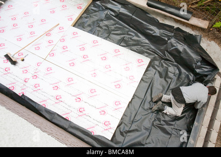 Builders lay under floor insulation into a house extension in Ambleside, UK. Stock Photo