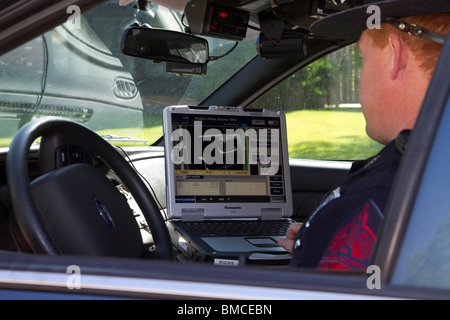 Nebraska State Trooper using laptop computer in cruiser to read output from an Automated License Plate Reader, LPR. Stock Photo