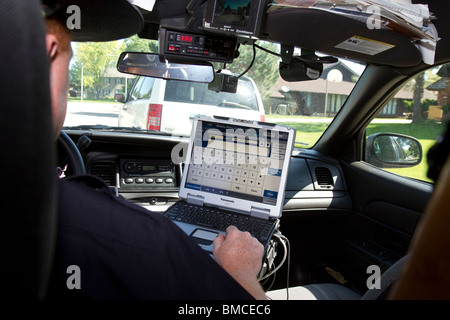 Nebraska State Trooper using laptop computer in cruiser to read output from an Automated License Plate Reader, LPR. Stock Photo