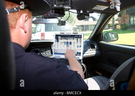 Nebraska State Trooper using laptop computer in cruiser to read output from an Automated License Plate Reader, LPR. Stock Photo