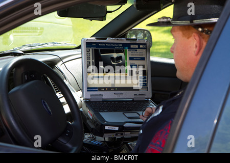 Nebraska State Trooper using laptop computer in cruiser to read output from an Automated License Plate Reader, LPR. Stock Photo