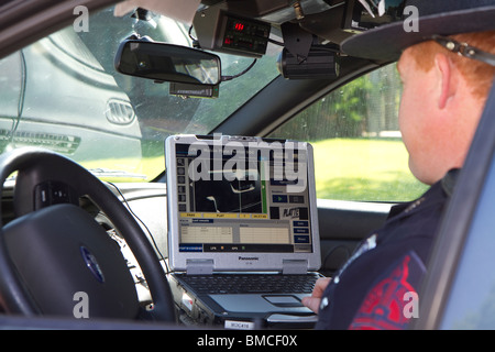 Nebraska State Trooper using laptop computer in cruiser to read output from an Automated License Plate Reader, LPR. Stock Photo