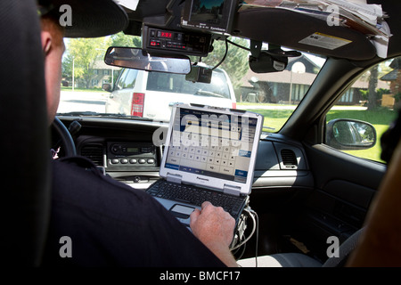 Nebraska State Trooper using laptop computer in cruiser to read output from an Automated License Plate Reader, LPR. Stock Photo