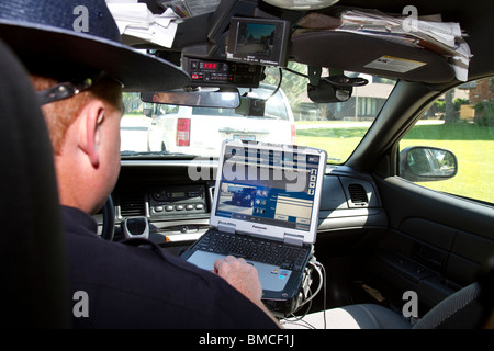 Nebraska State Trooper using laptop computer in cruiser to read output from an Automated License Plate Reader, LPR. Stock Photo