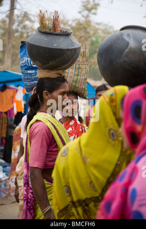 Women shopping rural village market India carry purchases in pots on heads dressed in sarees colourful ethnic costumes ethnic lifestyle Kahna India Stock Photo