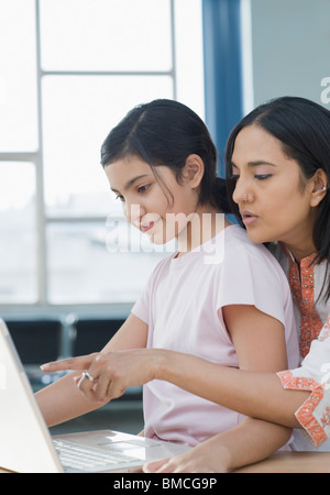 Girl sitting with her mother and using a laptop Stock Photo