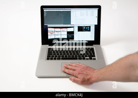 Hand & fingers moving across an old vintage Macbook Pro iBook Scrolling TrackPad / trackpad / track pad on an Apple laptop / lap top computer. Stock Photo