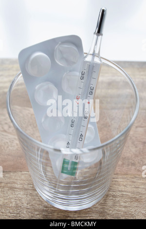 Pills and Thermometer in Glass Stock Photo