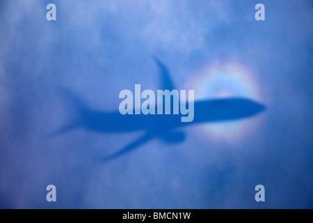 Glory of the Pilot shadow and halo around passenger jet from sun reflected on clouds and ice crystals in upper atmosphere Stock Photo