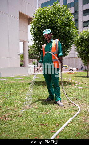 Asian man watering the lawn at Dubai Creek Stock Photo