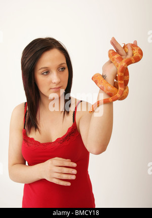 A Woman looking at a corn snake held in her hand Stock Photo