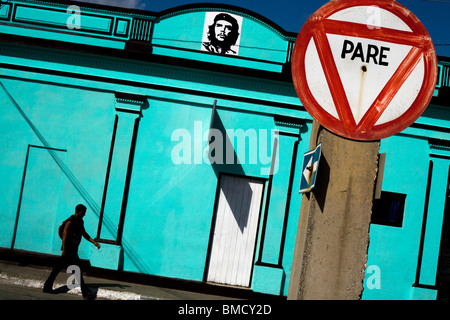 A man walks by a bright blue building adorned with an image of Ernesto Che Guevara in Baracoa, Cuba on Monday July 14, 2008. Stock Photo