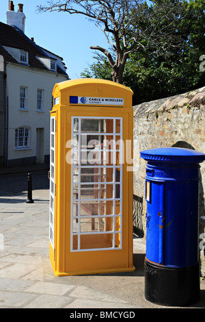 Yellow telephone box and blue letter box on High Street, St. Anne Alderney, Channel Island, United Kingdom Stock Photo