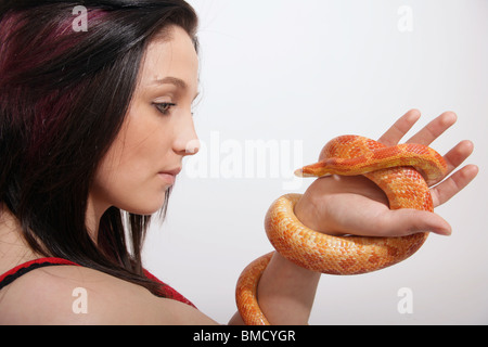 A Woman looking at a corn snake held in her hand Stock Photo