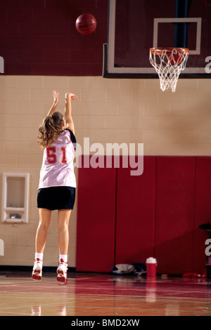 Teenage girl practicing basketball indoors, Stock Photo