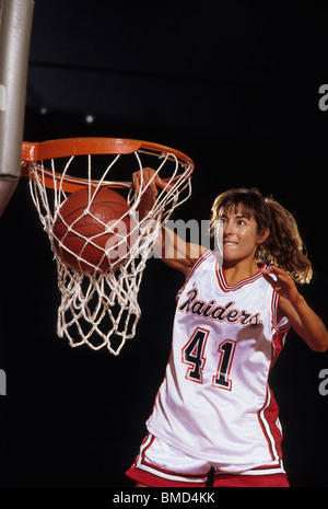 Female basketball player dunking a ball through the hoop, Stock Photo