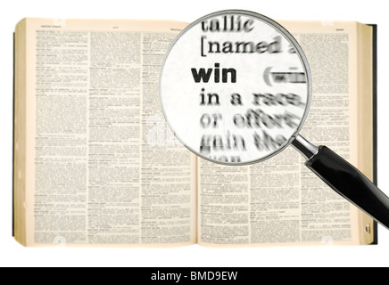 A magnifying glass on the word WIN on a dictionary. Isolated on white. Stock Photo