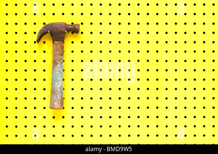 Old hammer with paint marks hangs from metal hook. Wooden handle with metal head. Stock Photo