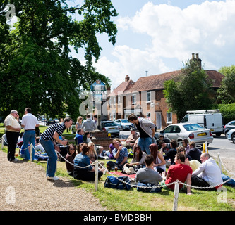 People sitting on the grass in Stock village in Essex.  Photo by Gordon Scammell Stock Photo