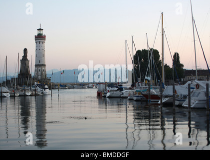 Lindau harbor entrance, marina and lighthouse on Lake Constance in Germany at dusk with reflections in the water Stock Photo