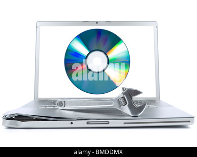 Damaged laptop with a spanner over it and a digital disc on the screen. Isolated on white. Stock Photo