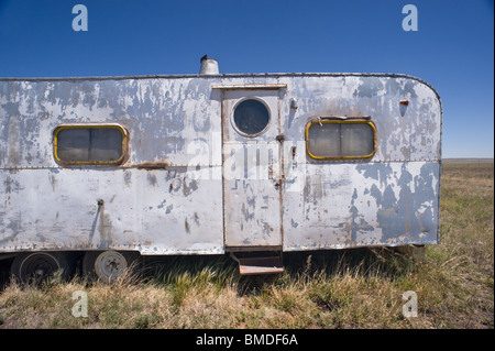 A frequent sight in New Mexico - a dented, paint-peeling, derelict camping trailer sitting in a weed-patch - Encino, New Mexico. Stock Photo