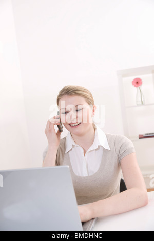 Woman Using Laptop and Cell Phone Stock Photo