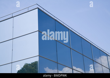 Modern glass building with trees and clouds reflected on it. Stock Photo