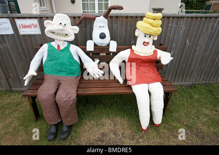 A Bakewell Tart - Wallace sat on bench with Piella Bakewell and Gromit looking from behind, Bisterne Annual Scarecrow Festival, Bisterne, Hampshire UK Stock Photo