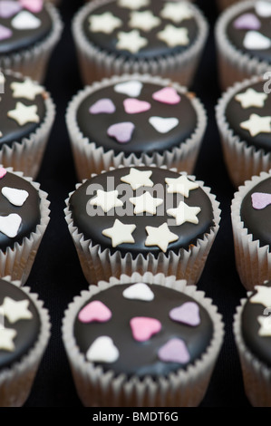 Mini cupcakes decorated with black icing, sugar hearts and white chocolate stars Stock Photo