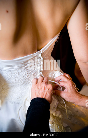 Woman buttoning up the bride's wedding dress Stock Photo