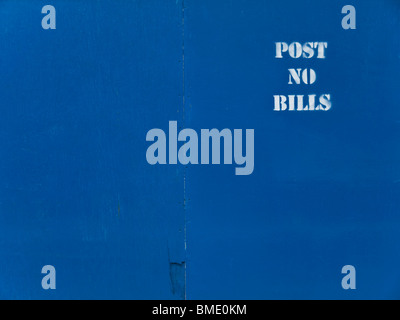 Blue wooden panel background with a white stenciled 'post no bills' text. Stock Photo
