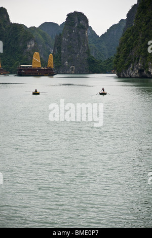 2 rowing boats approach a Junk Boat full of tourists on Halong Bay, Vietnam Stock Photo