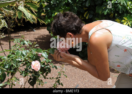 Senior lady smelling a rose in garden Stock Photo