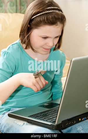 Young girl holding a poplar hawk moth and researching moths on a laptop in her lounge Stock Photo