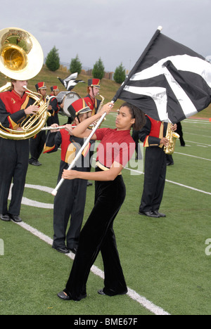 Girl carries a flag for the high school marching band during a half time show at a football game Stock Photo