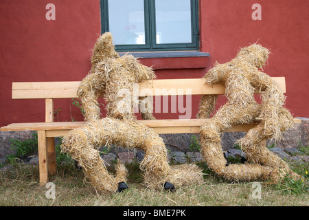 Two rough straw figures on a wooden bench. Stock Photo