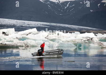 Man and dinghy in icy sea Stock Photo