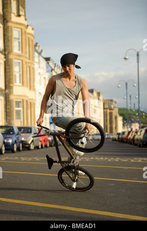 BMX flatland freestyle stunt rider young man performing stunts on his BMX bike, UK Stock Photo
