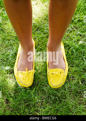 Woman standing on grass with yellow footwear, elevated view Stock Photo