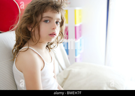 little brunette girl sit on sofa window light Stock Photo