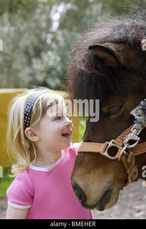 little blond girl loves her pony funny portrait Stock Photo