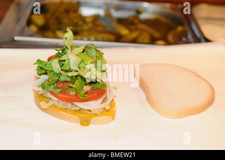 preparing a Kosher New York deli-style corned beef sandwich with shredded lettuce and tomato Stock Photo