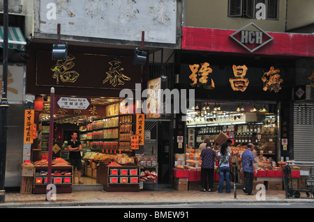 Afternoon shot of two illuminated dried seafood and Chinese medicine shops, Des Voeux Road West, Sai Ying Pun, Hong Kong, China Stock Photo