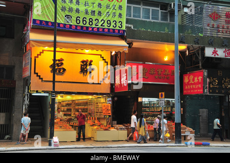 Two yellow, red, illuminated, open-fronted shops selling dried fish and seafood, Des Voeux Road West, Sai Ying Pun, Hong Kong Stock Photo