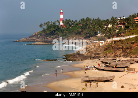 India, Kerala, Kovalam, Vizhinjam village fishing boats on beach in front of lighthouse Stock Photo