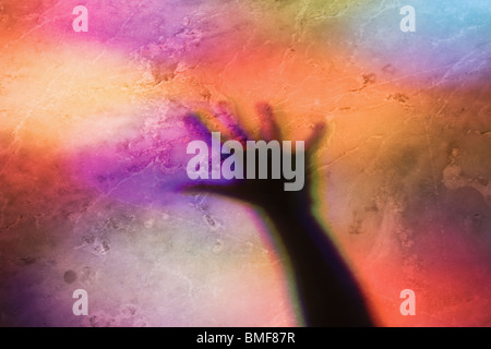 Shadow of outstretched hand on floor coloured by stained glass window. Stock Photo
